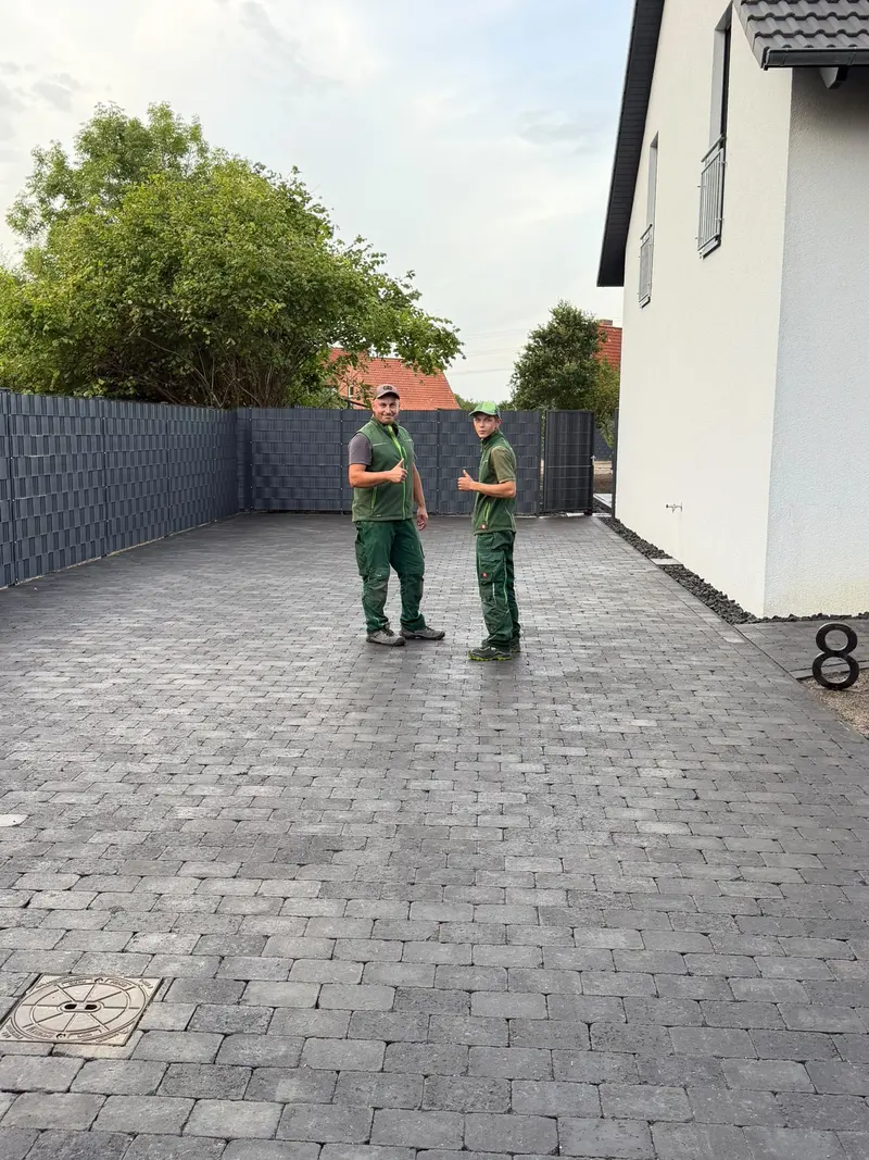 Zwei Mitarbeiter von Garten Team Krause auf der fertig gepflasterten Hoffläche